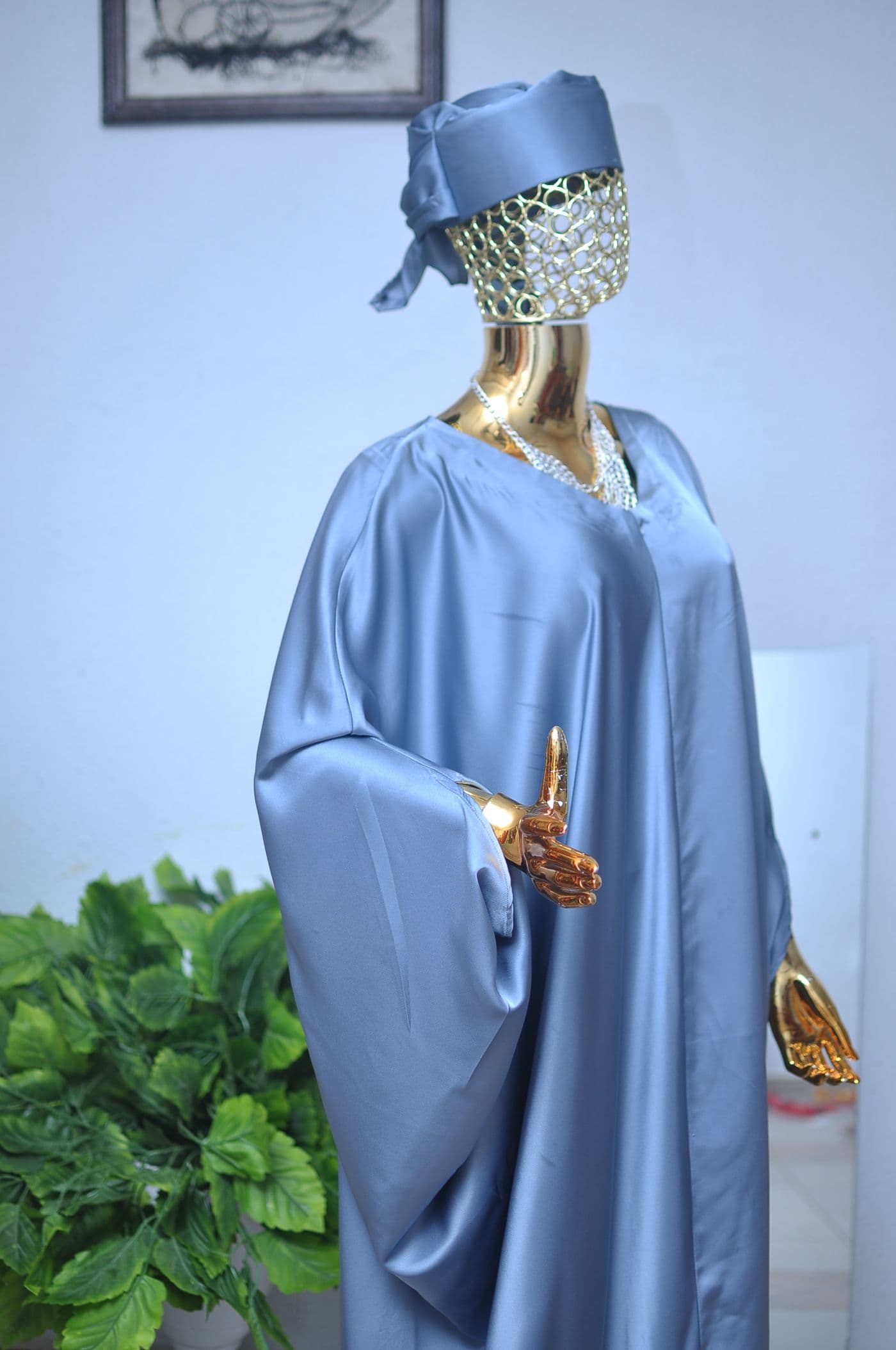 Slate-blue satin gown with a crystal-set neckline, on a gold mannequin.